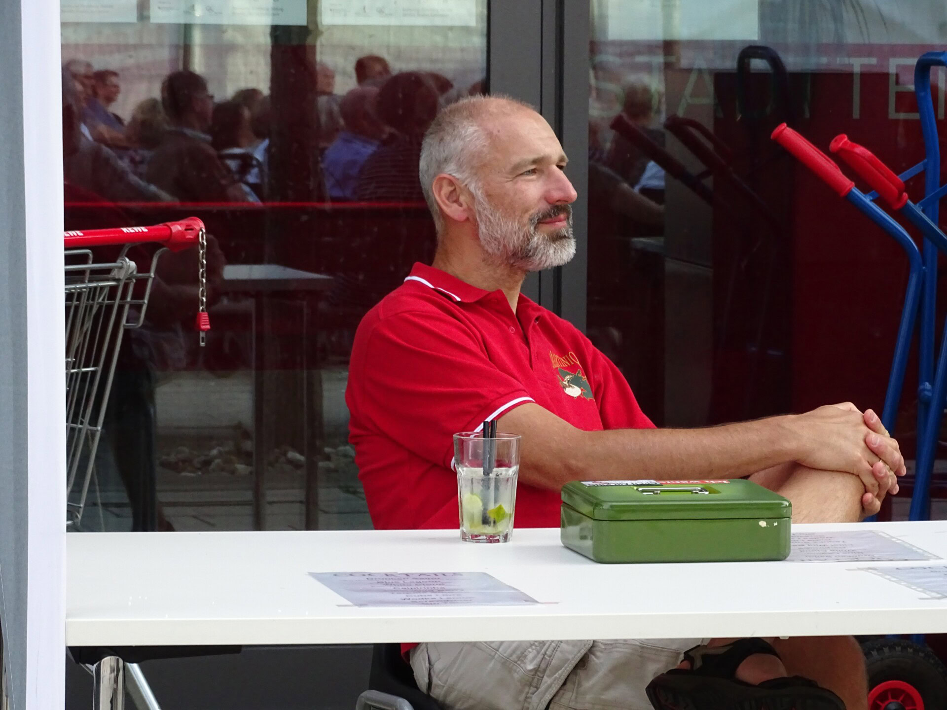 Mann sitzt an einem Tisch mit Getränk.