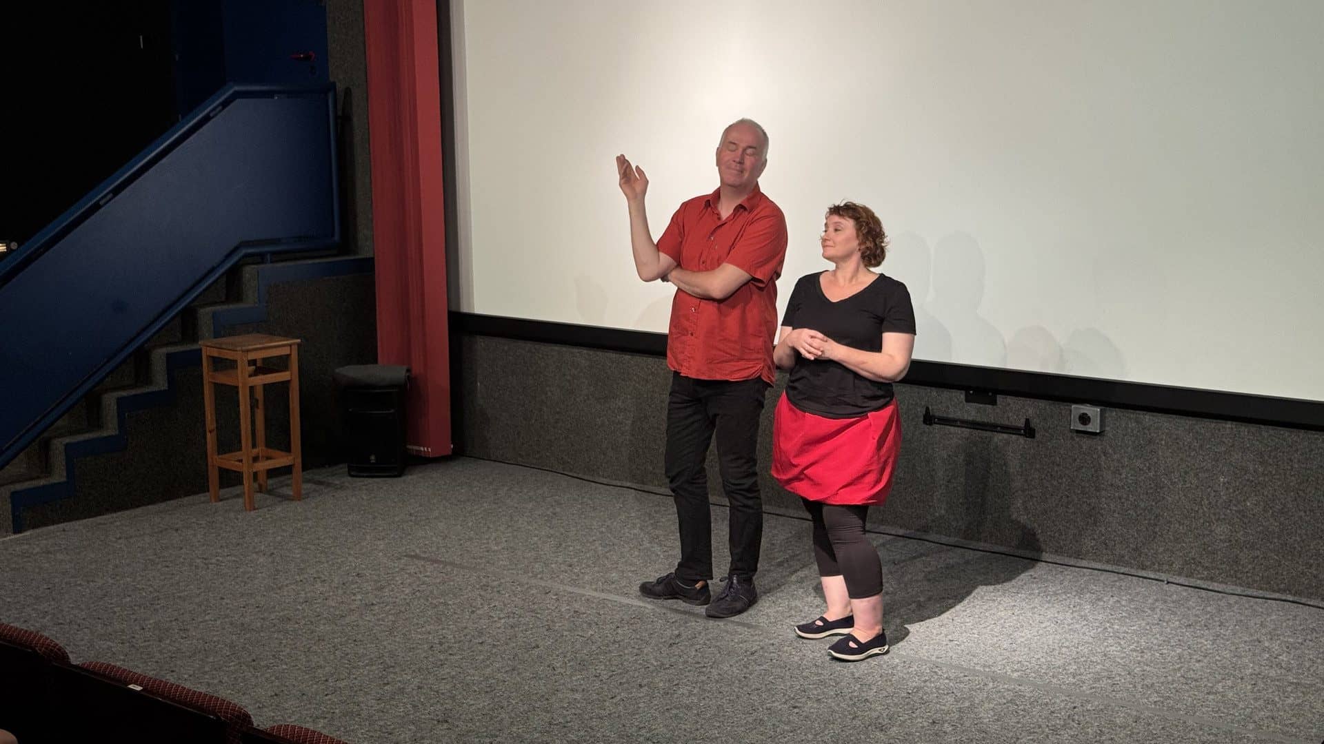 Zwei Personen präsentieren auf einer Bühne im Kino.
