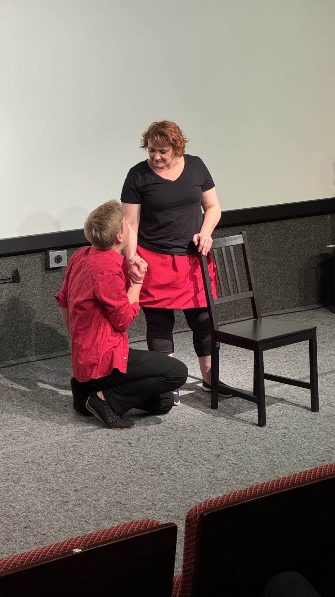Zwei Personen führen eine Theaterszene auf der Bühne auf.