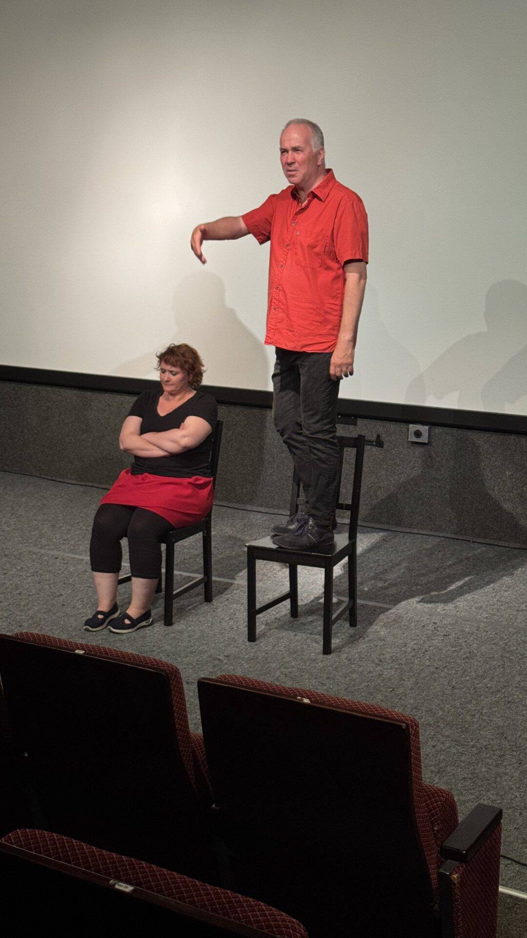 Zwei Personen führen ein Theaterstück auf einer Bühne auf.