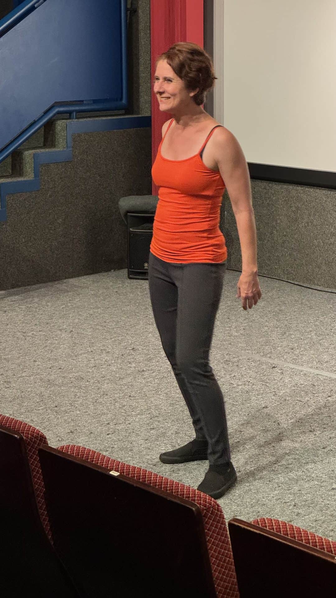 Frau auf Bühne in Theaterkulisse stehend, lächelnd