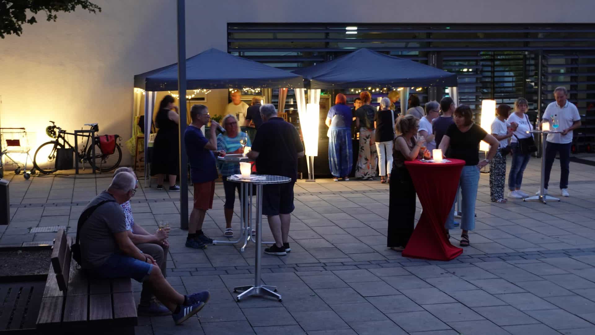 Nachtveranstaltung mit Menschen und beleuchteten Zelten.