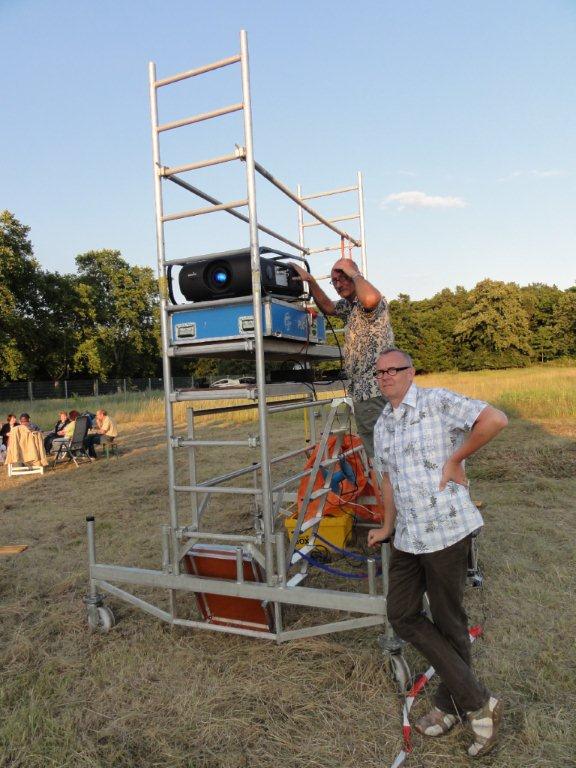 Zwei Männer arbeiten an einem Außenprojektor im Freien.