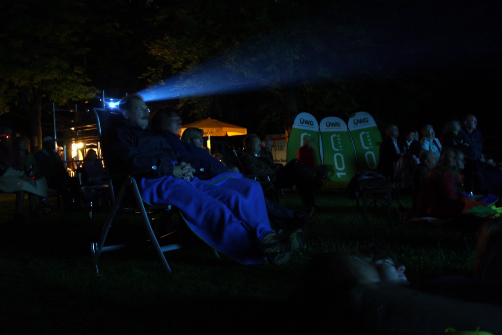 Menschen schauen Film im Freien bei Nacht.