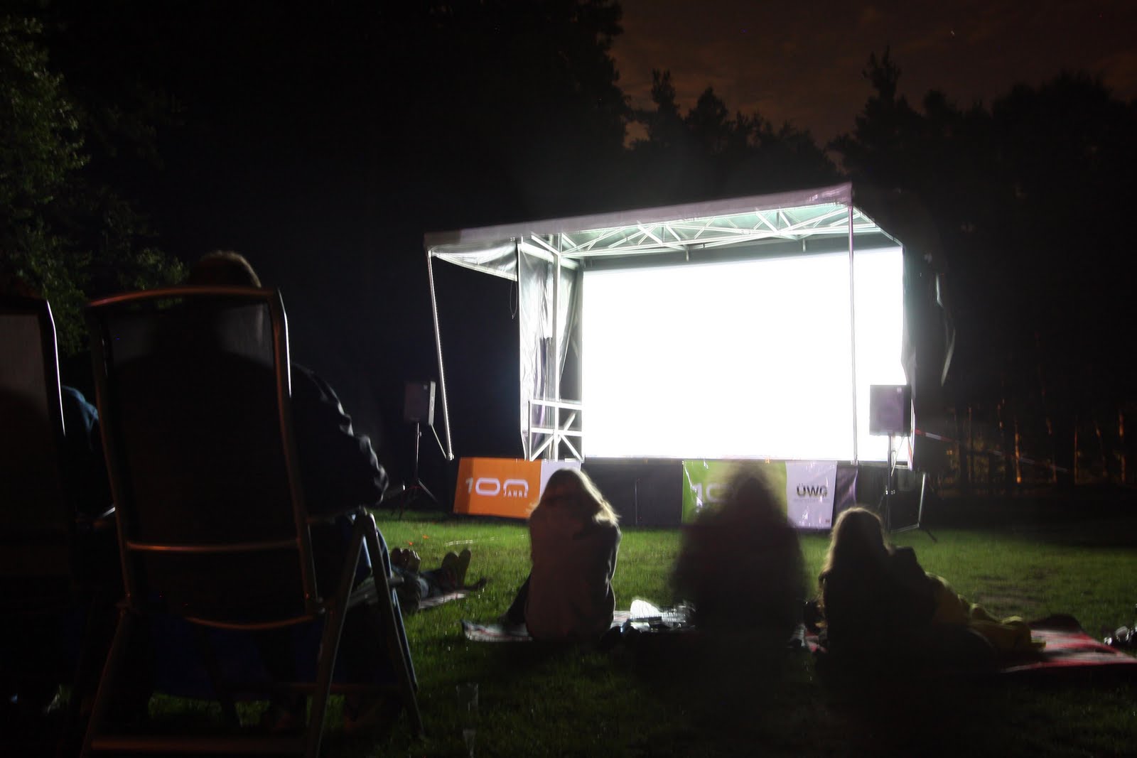 Menschen schauen nachts einen Film im Freien