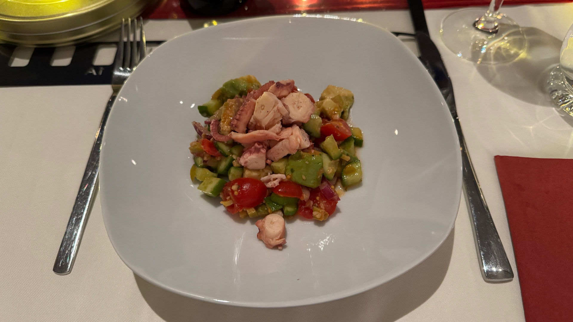 Mediterraner Tintenfischsalat mit Gemüse in weißem Teller
