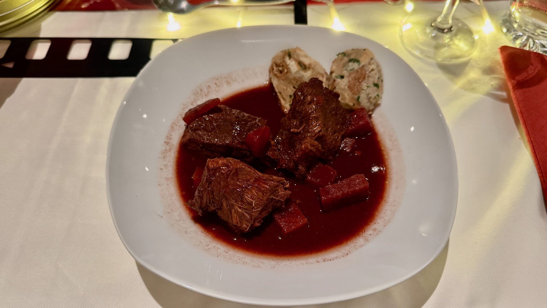 Rindergulasch mit Knödel auf weißem Teller