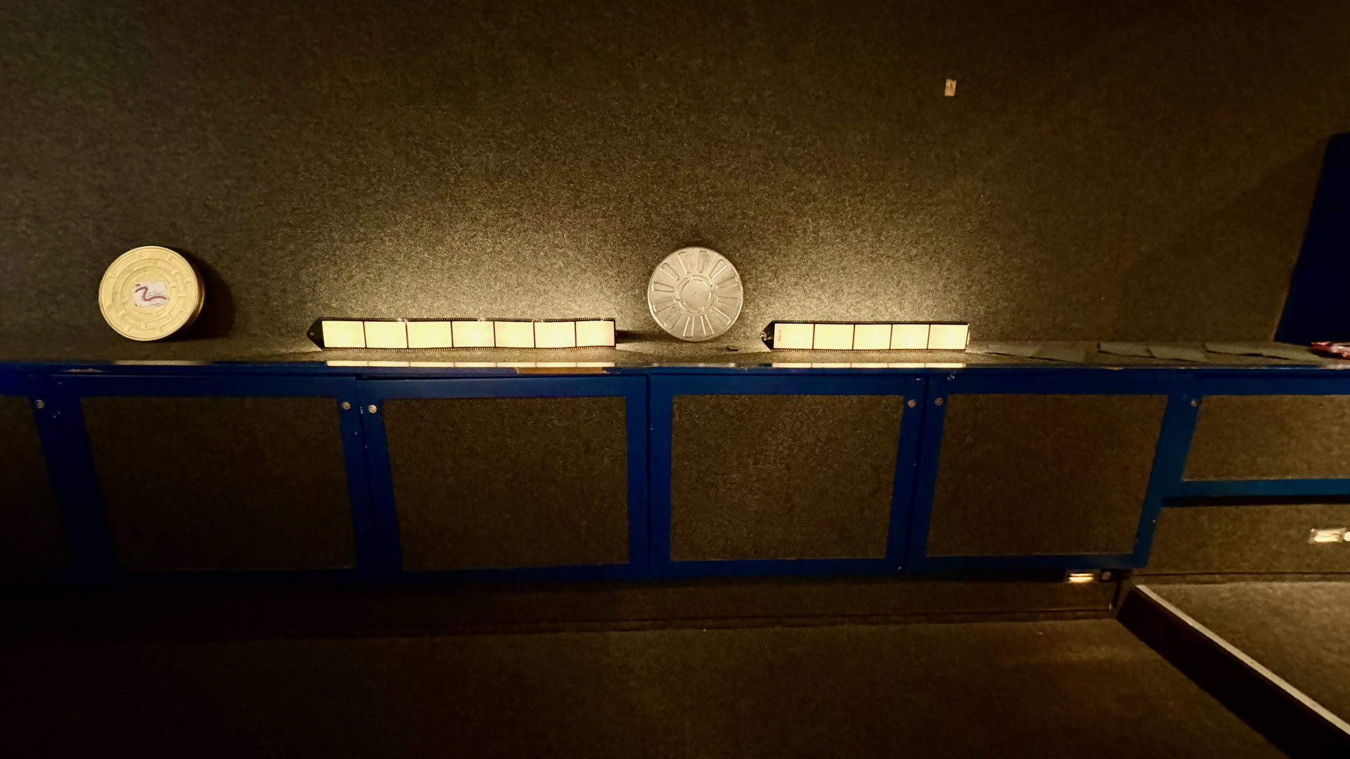 Tisch mit belichteten Lichtkästen in dunklem Raum.