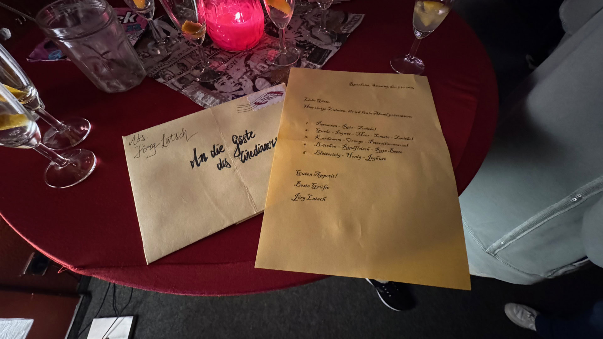 Gelbe Umschläge auf rotem Tisch bei Kerzenlicht