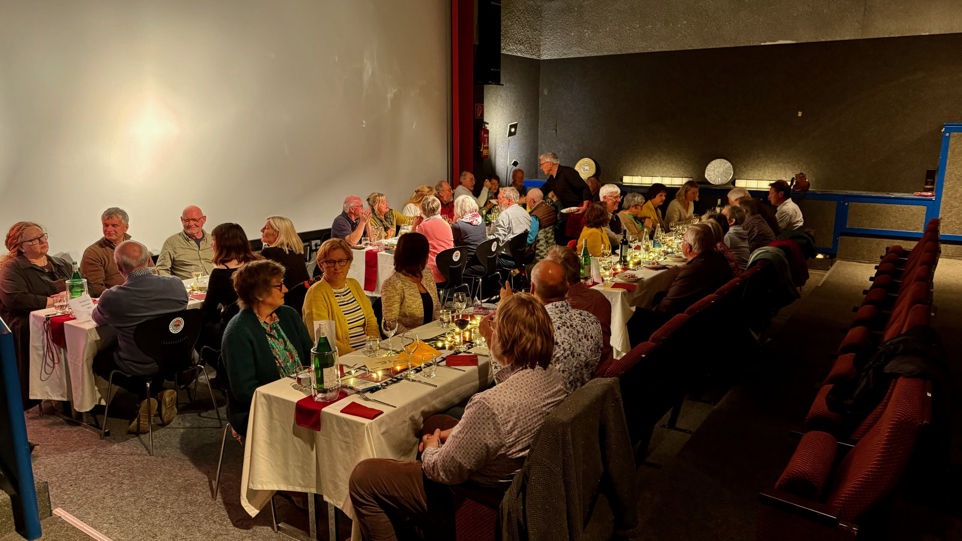Personen bei festlichem Abendessen im Kinosaal