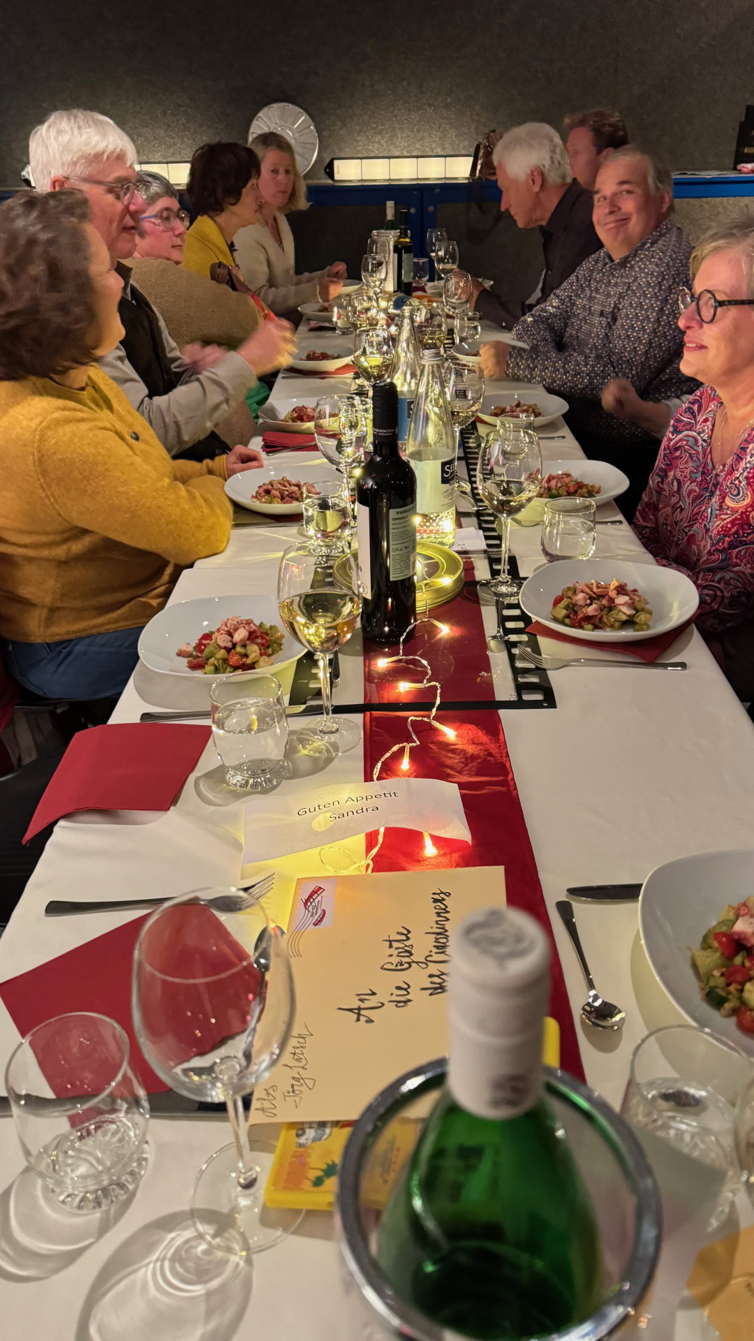 Menschen genießen gemeinsames Abendessen an festlich gedecktem Tisch.