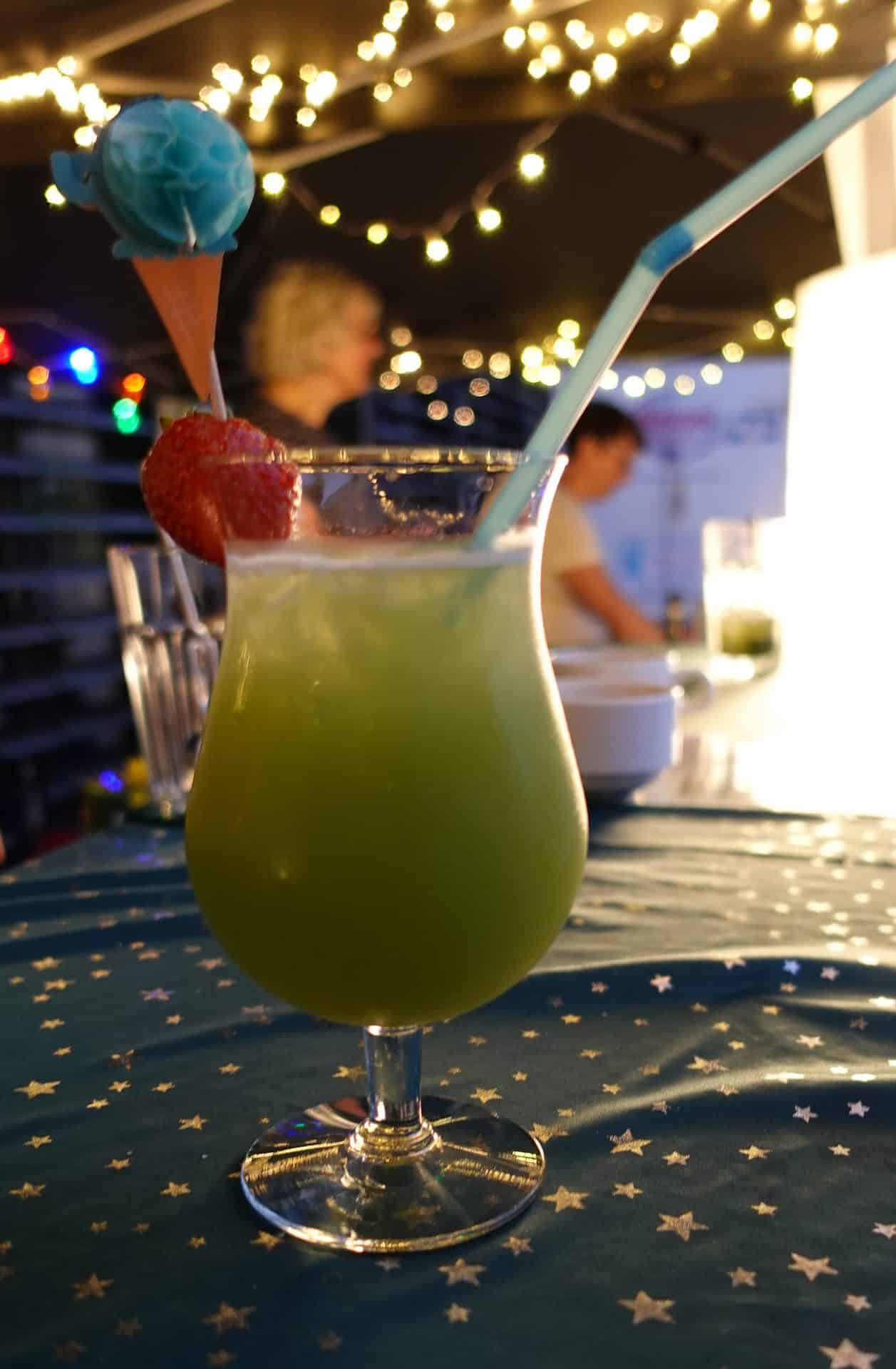 Grüner Cocktail mit Erdbeere auf Sternentisch.