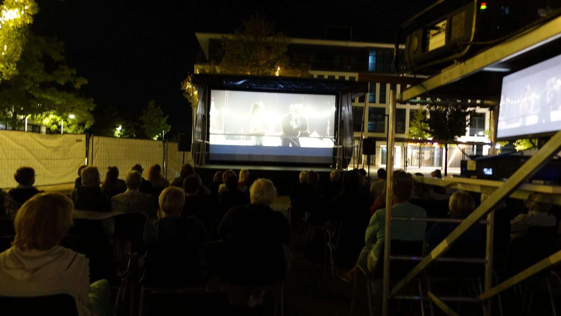 Menschen schauen nächtlichen Outdoor-Film im Freien.