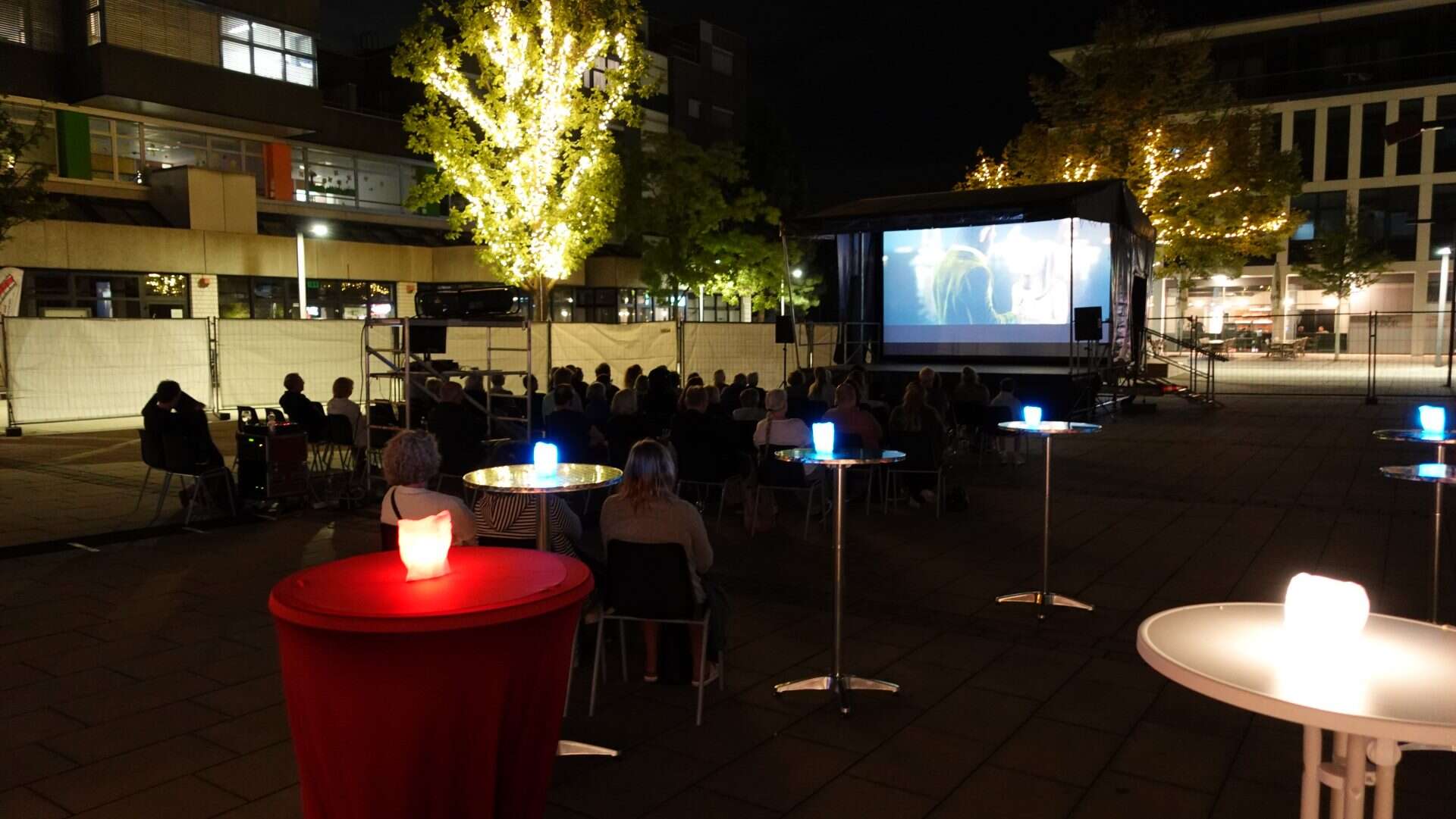 Open-Air-Kino bei Nacht mit Publikum und Beleuchtung.