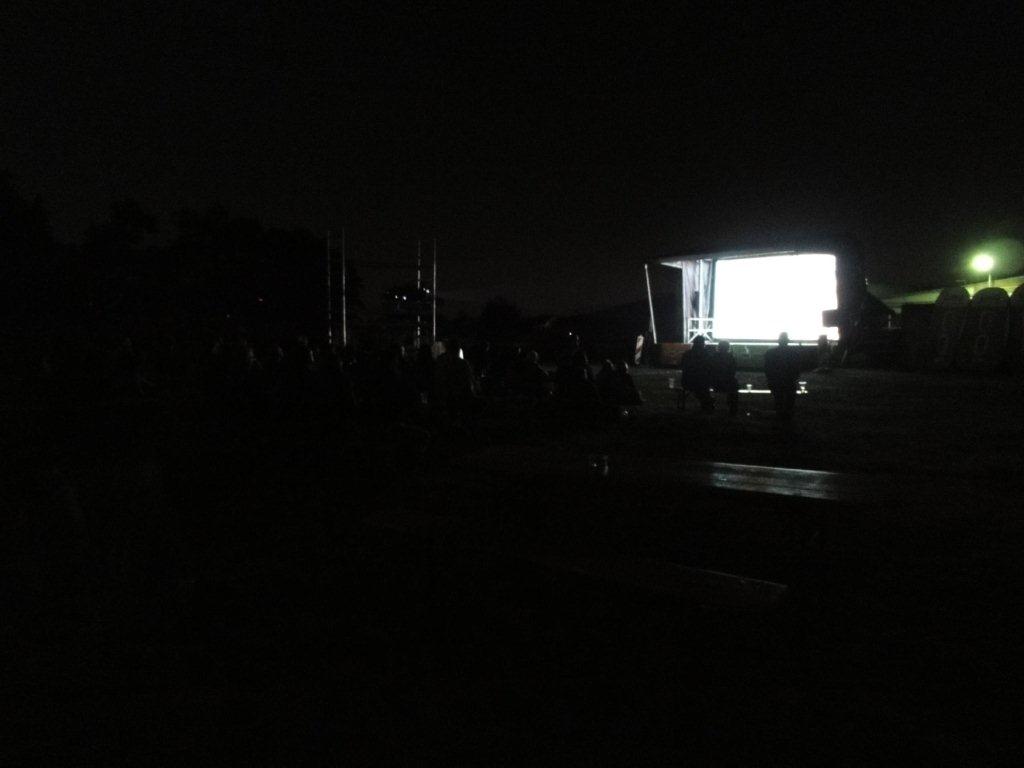 Menschen schauen einen Film im Freien bei Nacht.