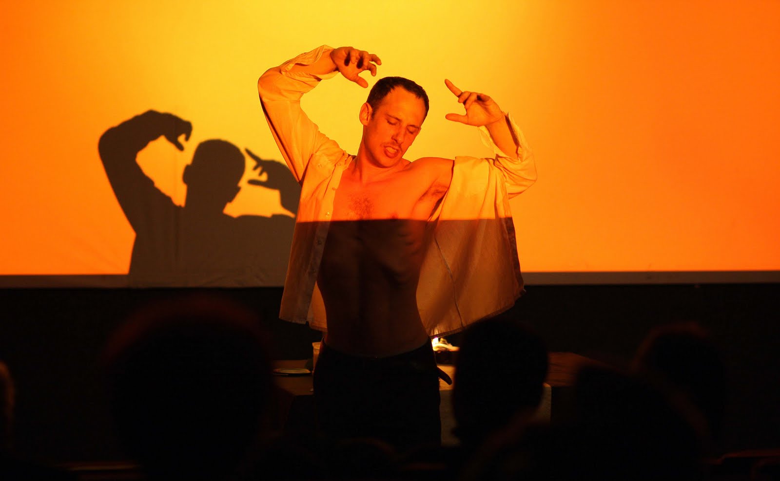 Mann tanzt energisch vor oranger Leinwand