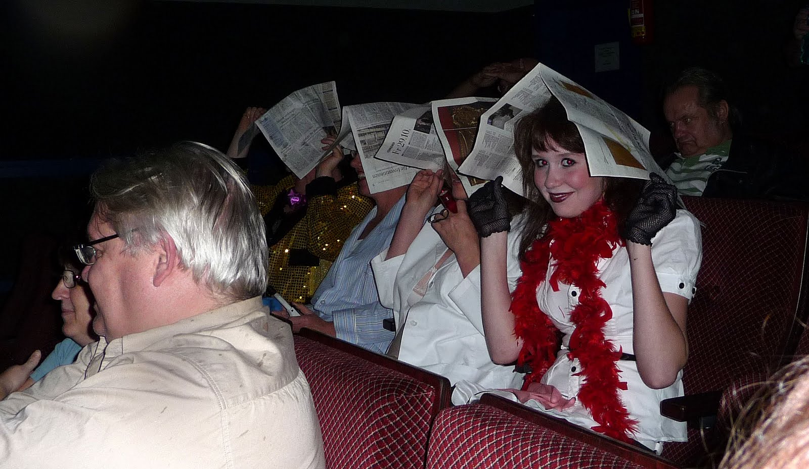 Menschen verstecken sich hinter Zeitungen im Kino.