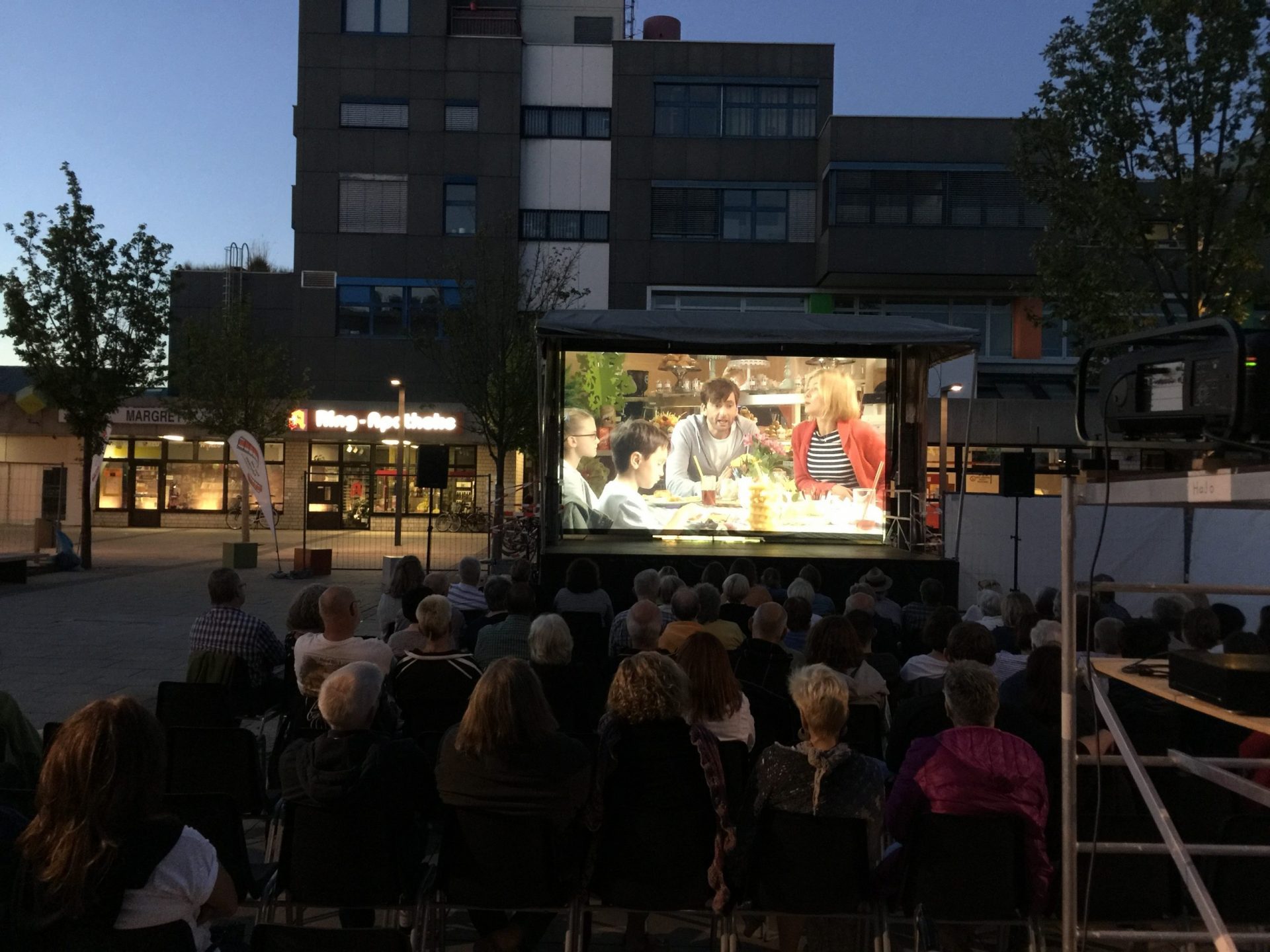 Menschen sehen abends einen Film im Freien an.
