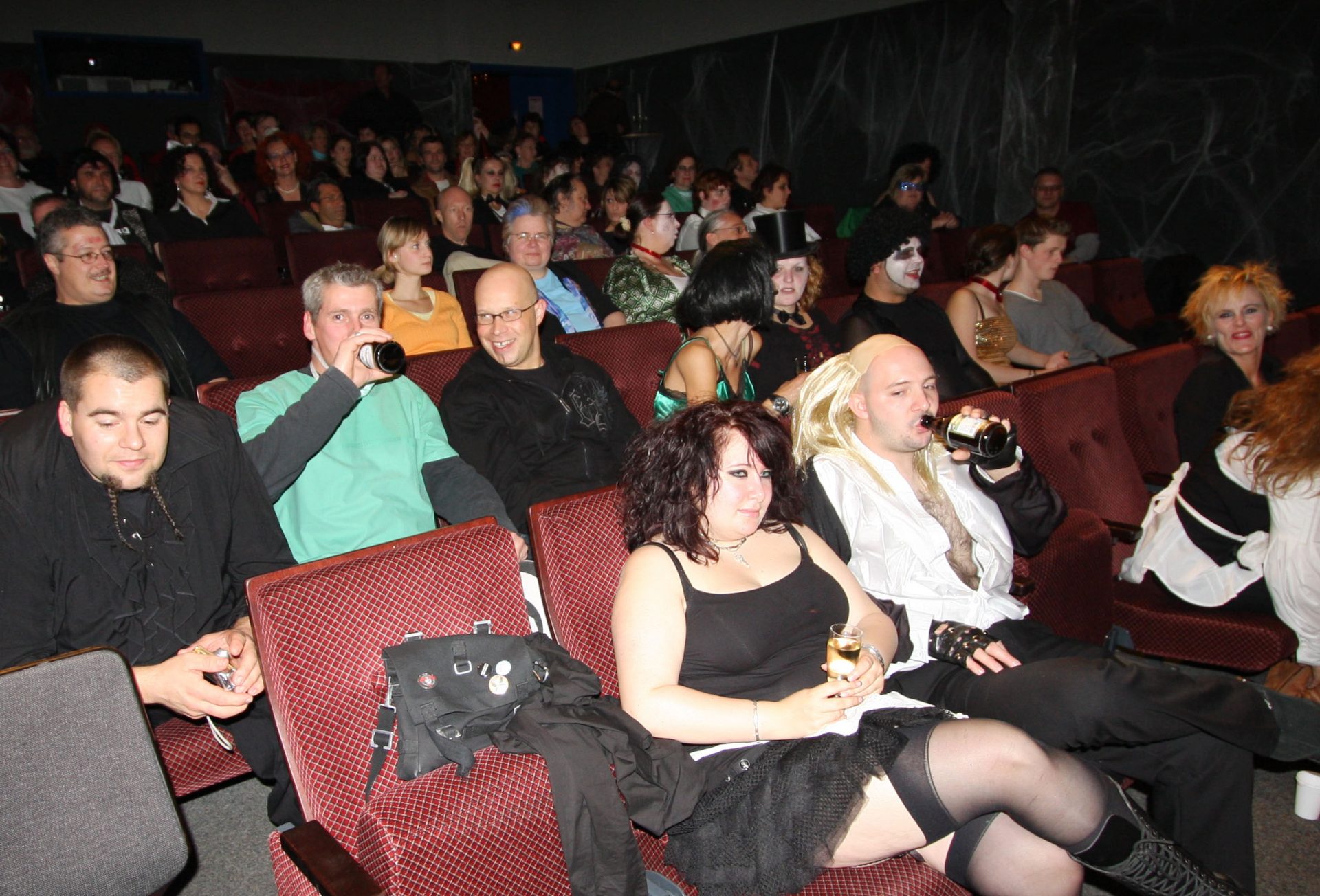 Menschen in Verkleidung im Kino sitzen.