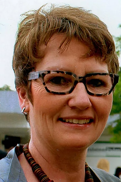 Frau mit Brille und kurzen Haaren lächelt.