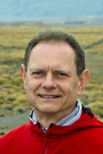 Mann in Natur mit rotem Pullover lächelt