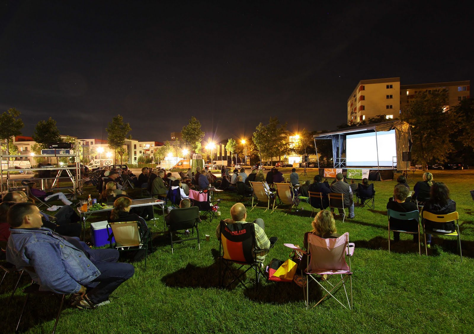 Menschen genießen ein Freiluftkino bei Nacht.